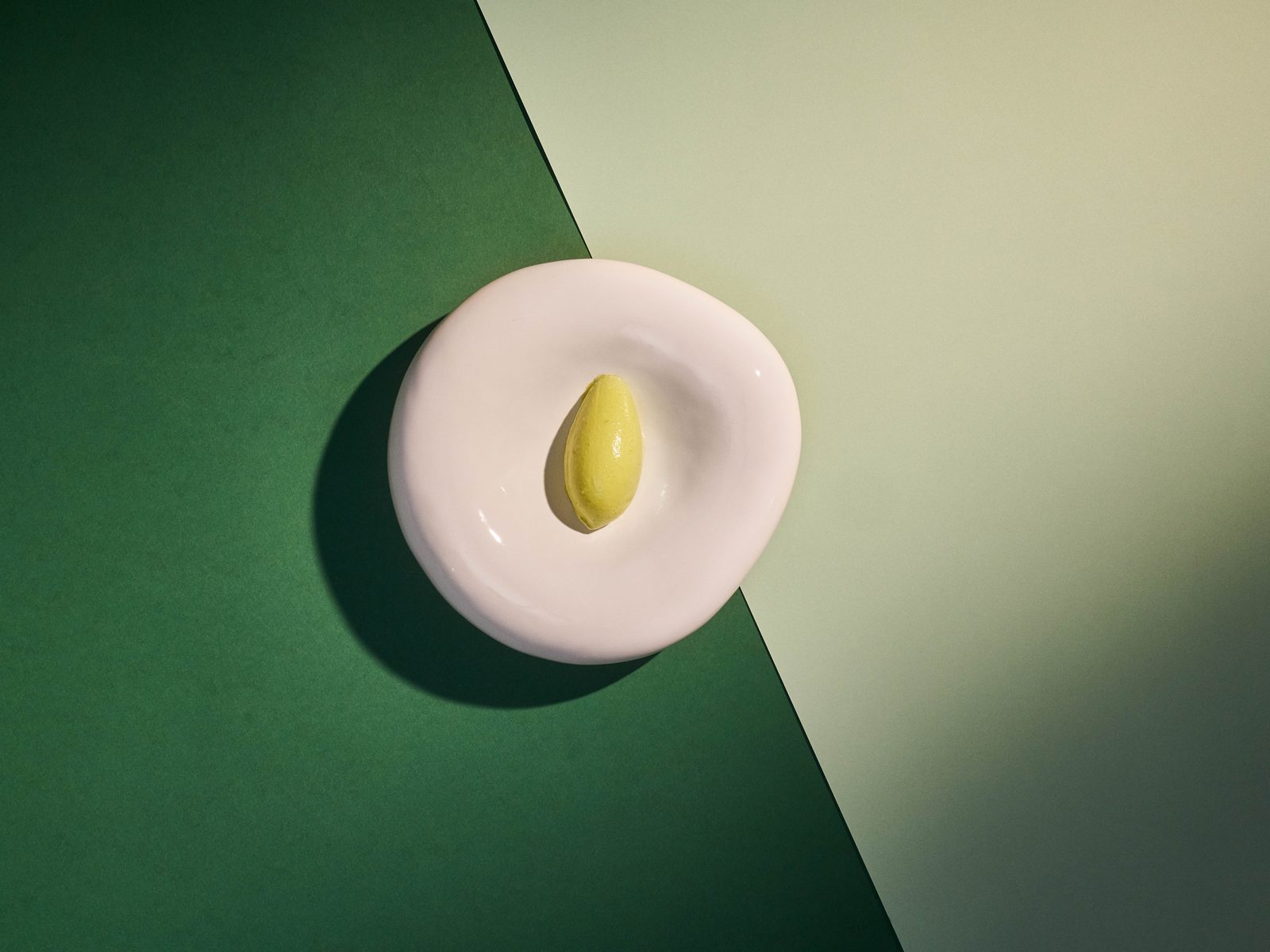 Grüne-Sauce-Eis als perfekte Quenelle auf weißer Keramik